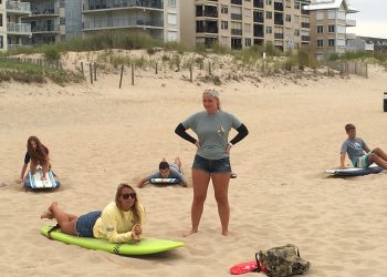 Instructors giving students surf lessons