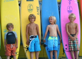 kids standing in front of different colored surfboards