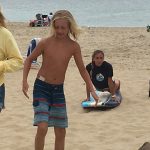 A young boy taking surf lessons on the beach