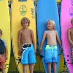 kids standing in front of different colored surfboards