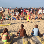 a group observing a man standing next to surfboard