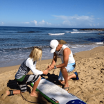instructor talking to student above surfboard on the beach